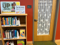 A collection of pop-up books for children on a small bookcase next to a door.