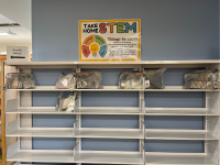 Empty shelves with a sign above the shelves reading "Take Home STEM"