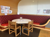 A white round table, two chairs, and the table in the corner of a bench on the wall