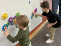 two children playing with suction gears on a whiteboard