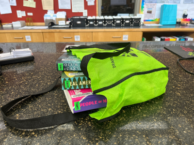 Lime green bag holding multiple large books lying on the counter