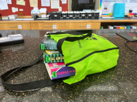 Lime green bag holding multiple large books lying on the counter