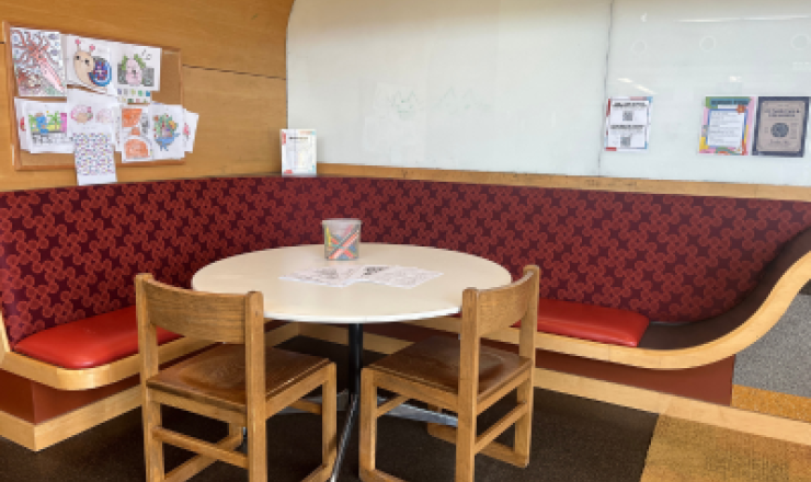 A white round table, two chairs, and the table in the corner of a bench on the wall