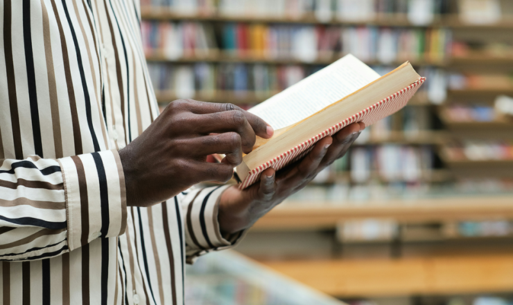 image of a man's hands holding an open book in the library